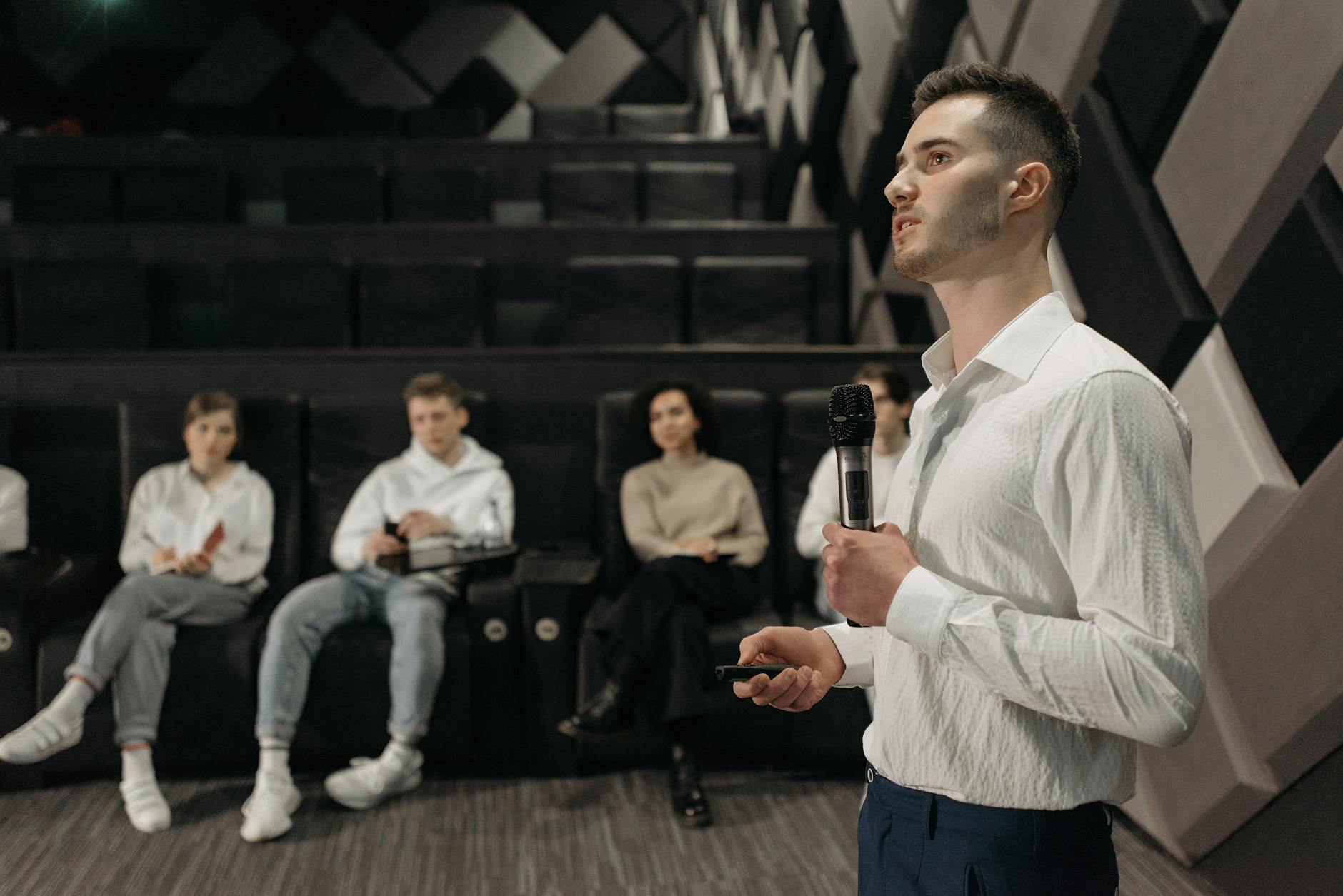 Man in white dress shirt holding microphone doing a presentation